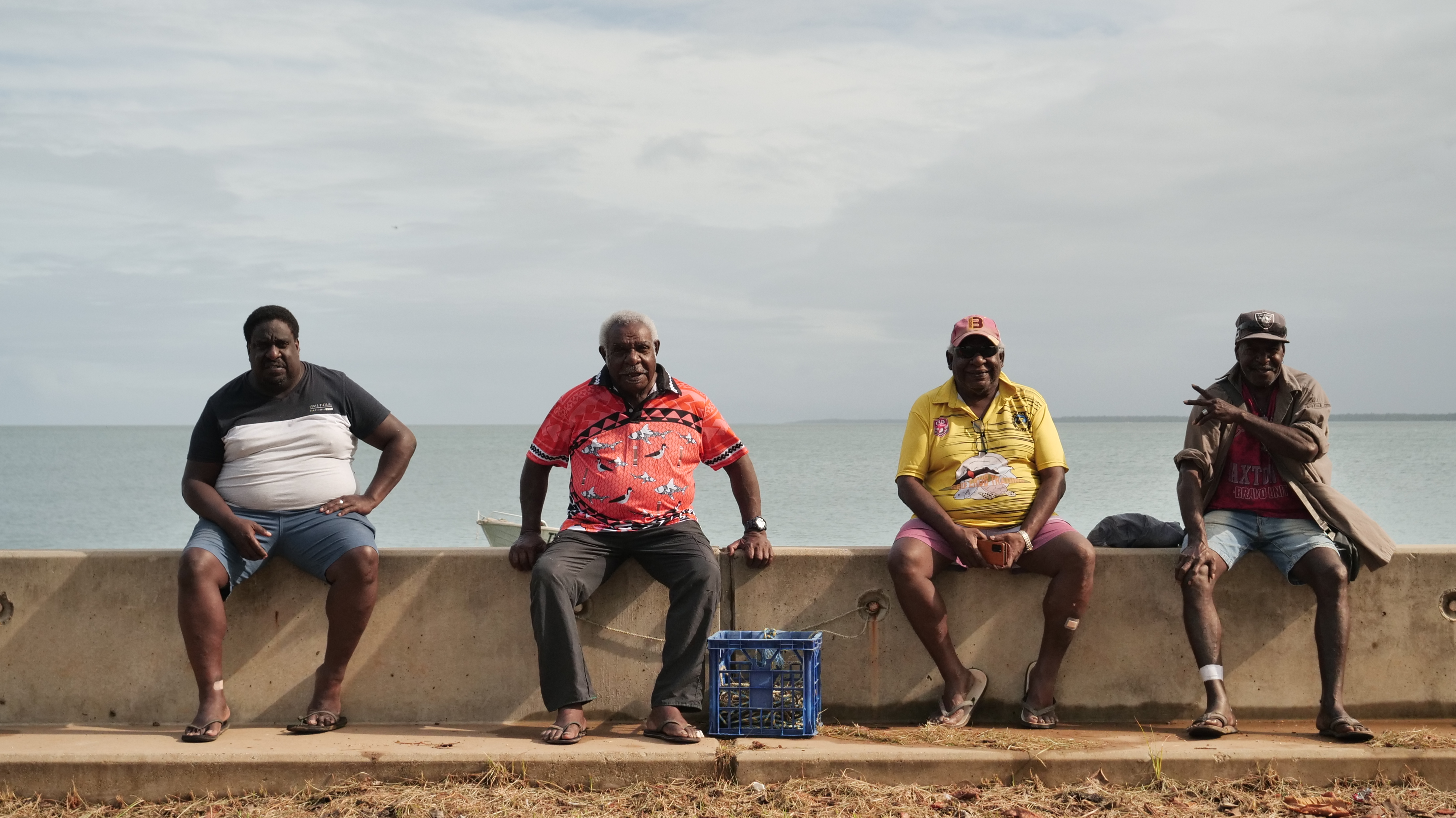 Saibai locals, Eliab Dai, Nemiah Dai, Edward Sam and Samuel Gibia wait for court to set up on the sea wall. (Grata Fund, Ruby Mitchell)
