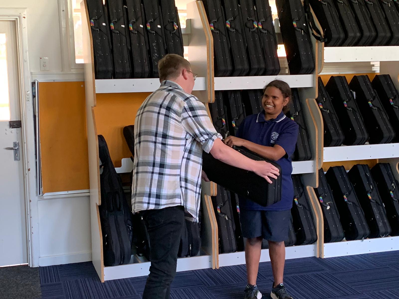 Sandra receiving a violin as a parting gift from WASO Crescendo teacher Griffin Wright.